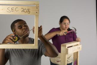 undergraduate students measure and hammer set pieces