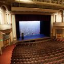 Large theatre with empty stage as viewed from the rear balcony of the house